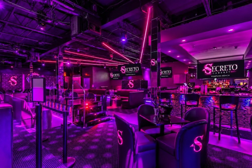 Main room of Secreto Cabaret with pink neon, bar, and lounge seating